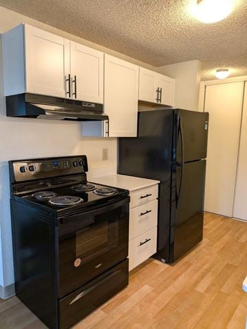 Tualatin apartment for rent - A black stove and refrigerator in a kitchen with white cabinets.
