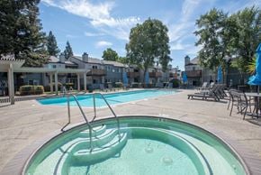 Citrus Heights apartment for rent - A hot tub sits in the middle of a pool area with a building in the background at Sierra Glen Apartments, California, 95621