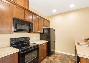 Oregon City townhouse for rent - A kitchen with black appliances and wooden cabinets.