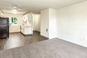 Tualatin apartment for rent - A kitchen with a black fridge and a living room with grey carpet at Todd Village Apartments, Oregon, 97062