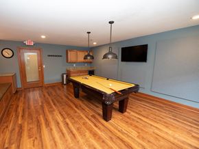 Menomonee Falls apartment for rent - A pool table in a room with wood flooring and a clock on the wall.