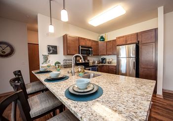 Open-concept kitchens with stainless steel appliances, kohler gooseneck faucets, and countertops featuring either granite or quartz