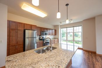 Open-concept kitchens with stainless steel appliances, kohler gooseneck faucets, and countertops featuring either granite or quartz