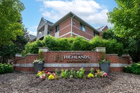 De Pere apartment for rent - The image shows a brick building with a sign that reads "Nicolet Highlands Apartments 55+".