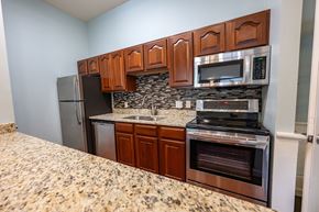 De Pere apartment for rent - A kitchen with brown cabinets and a granite countertop.