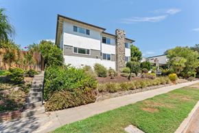 Pasadena apartment for rent - A house with a white and grey exterior and a stone pillar in the front yard.