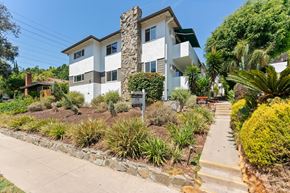 Pasadena apartment for rent - A white two-story house with a stone chimney and a green lawn.