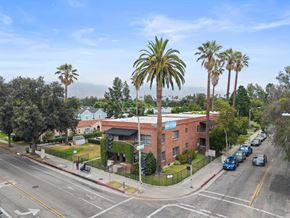Pasadena apartment for rent - A street view with a red brick building and palm trees.