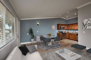 El Cajon apartment for rent - A modern living room with a grey sofa and a dining table set up.