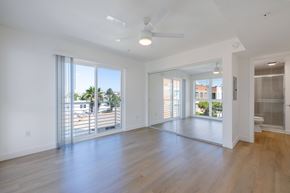 San Diego apartment for rent - A spacious room with a ceiling fan and sliding glass doors leading to a balcony.