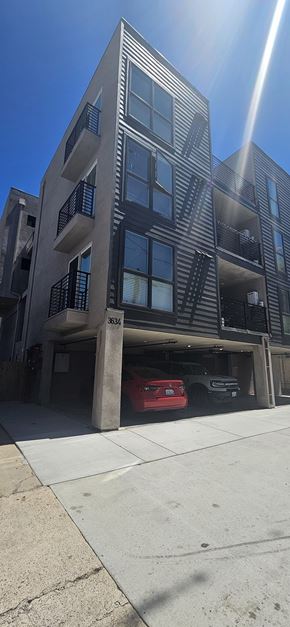 San Diego apartment for rent - A tall building with a red car parked on the side.
