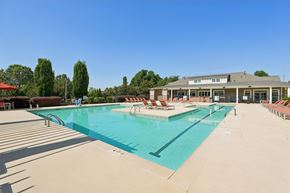 Mebane apartment for rent - A large swimming pool with lounge chairs and a building in the background.