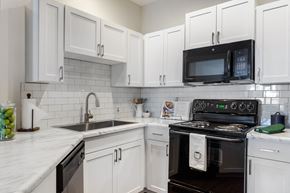 Charlotte apartment for rent - a kitchen with white cabinets and black appliances