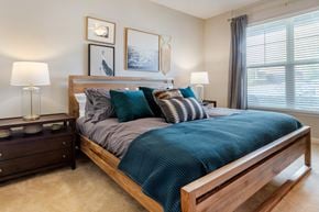Charlotte apartment for rent - a bedroom with a large window and a bed with a blue comforter