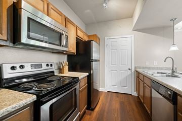 Denton apartment for rent - A kitchen with a black stove top oven and a black refrigerator.