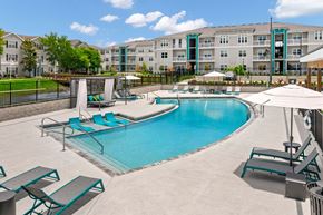 Tampa apartment for rent - a swimming pool with lounge chairs and umbrellas in front of an apartment building