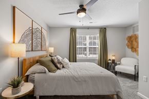 Greensboro apartment for rent - A bedroom with a bed, a ceiling fan, and a chair.