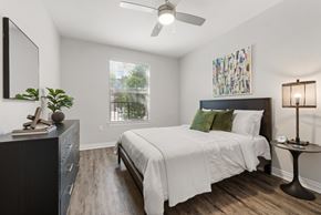 Irving apartment for rent - A bedroom with a bed, a dresser, a ceiling fan, and a painting on the wall.