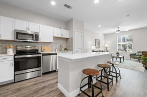 Irving apartment for rent - A kitchen with white cabinets and a white island with bar stools.