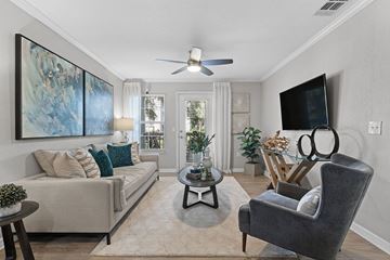Tampa apartment for rent - A living room with a grey couch, a black chair, a coffee table, and a painting on the wall.