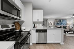 Tampa apartment for rent - A modern kitchen with a black stove top oven and white cabinets.