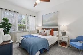 Sandy Springs apartment for rent - A bedroom with a bed, chair, and painting on the wall.