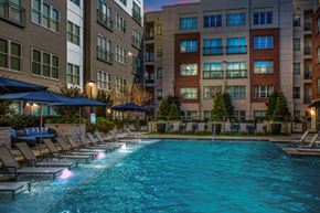 Sandy Springs apartment for rent - A swimming pool surrounded by lounge chairs and umbrellas in front of apartment buildings.