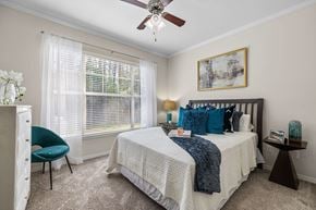 Jacksonville apartment for rent - A bedroom with a bed, chair, and a ceiling fan.