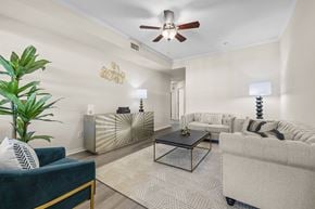 Jacksonville apartment for rent - A living room with a blue couch, a coffee table, and a ceiling fan.