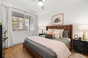 Denver apartment for rent - A bedroom with a large bed and a picture of a tree on the wall.