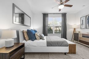 Plano apartment for rent - A bedroom with a large bed, a ceiling fan, and a window with curtains.