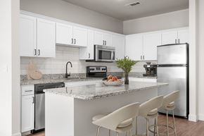 Plano apartment for rent - A kitchen with white cabinets and a granite countertop.