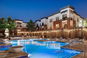 Plano apartment for rent - A large swimming pool with a waterfall in the middle of it.
