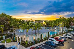 Miami apartment for rent - A sunset view of a parking lot with cars and a pool.