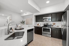 Miami apartment for rent - A modern kitchen with black cabinets and stainless steel appliances.