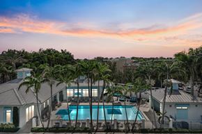 Miami apartment for rent - A beautiful house with a pool surrounded by palm trees.