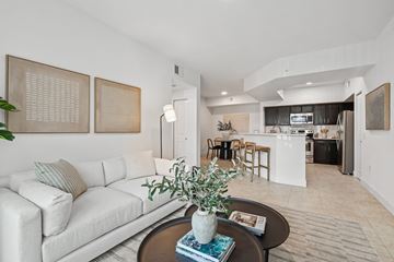 Miami apartment for rent - A living room with a white couch and a coffee table with a plant on it.