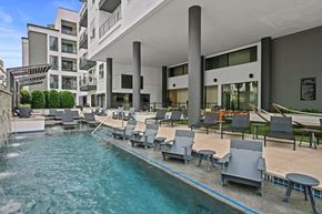 Dallas apartment for rent - a swimming pool with lounge chairs and umbrellas in front of an apartment building