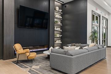 Miramar apartment for rent - A modern living room with a grey sofa, a yellow chair, and a black television mounted on the wall.