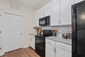 Mooresville apartment for rent - a kitchen with white cabinets and black appliances