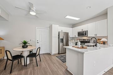 Murrieta apartment for rent - A kitchen with a table and chairs in the foreground and a refrigerator, microwave, and oven in the background.