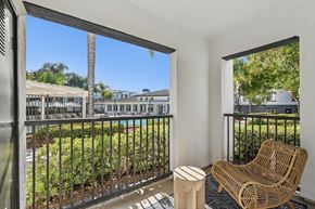 Murrieta apartment for rent - A balcony with a chair and table overlooking a pool and buildings.