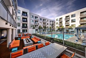 Pasadena apartment for rent - A modern outdoor seating area with orange cushions and a pool in the background.