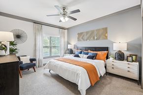 Fort Worth apartment for rent - A bedroom with a large bed, a ceiling fan, and a nightstand with a lamp.