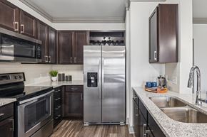 Fort Worth apartment for rent - A modern kitchen with a stainless steel refrigerator and wooden cabinets.