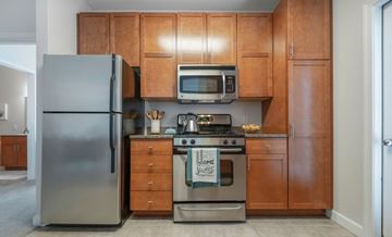 Reading apartment for rent - A kitchen with a stainless steel refrigerator, a microwave, and a stove with a sign on it.