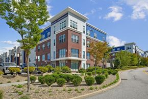 Shrewsbury apartment for rent - A modern multi-story building with a parking lot in front.