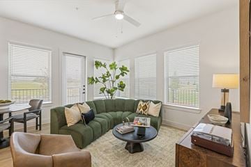 Frisco apartment for rent - A living room with a green couch and a ceiling fan.