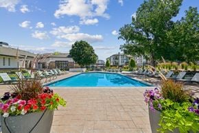 Parker apartment for rent - A pool surrounded by chairs and flowers with a building in the background.