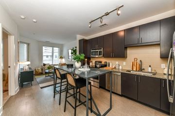 Atlanta apartment for rent - a kitchen with an island and stools and a living room with a couch